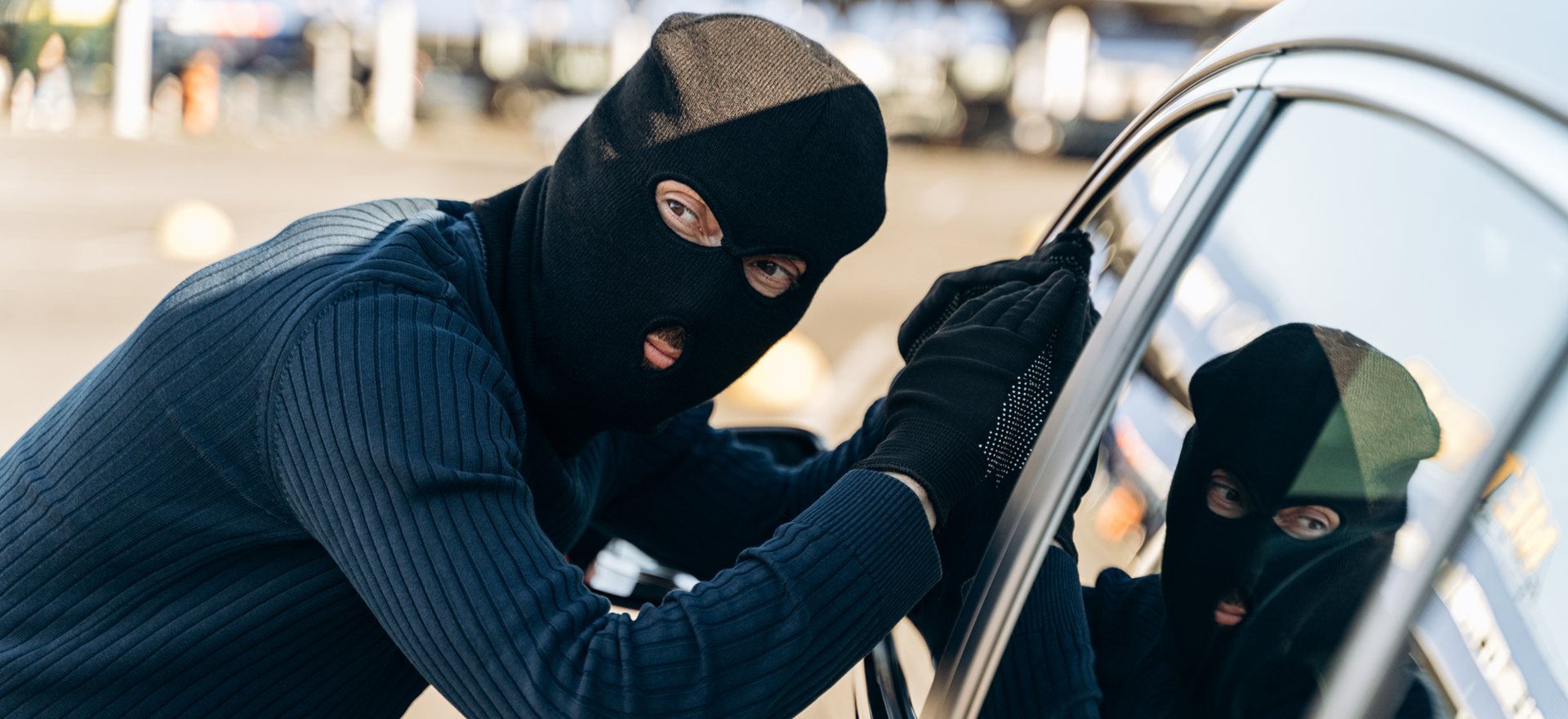 ein Dieb versucht ein Auto aufzubrechen