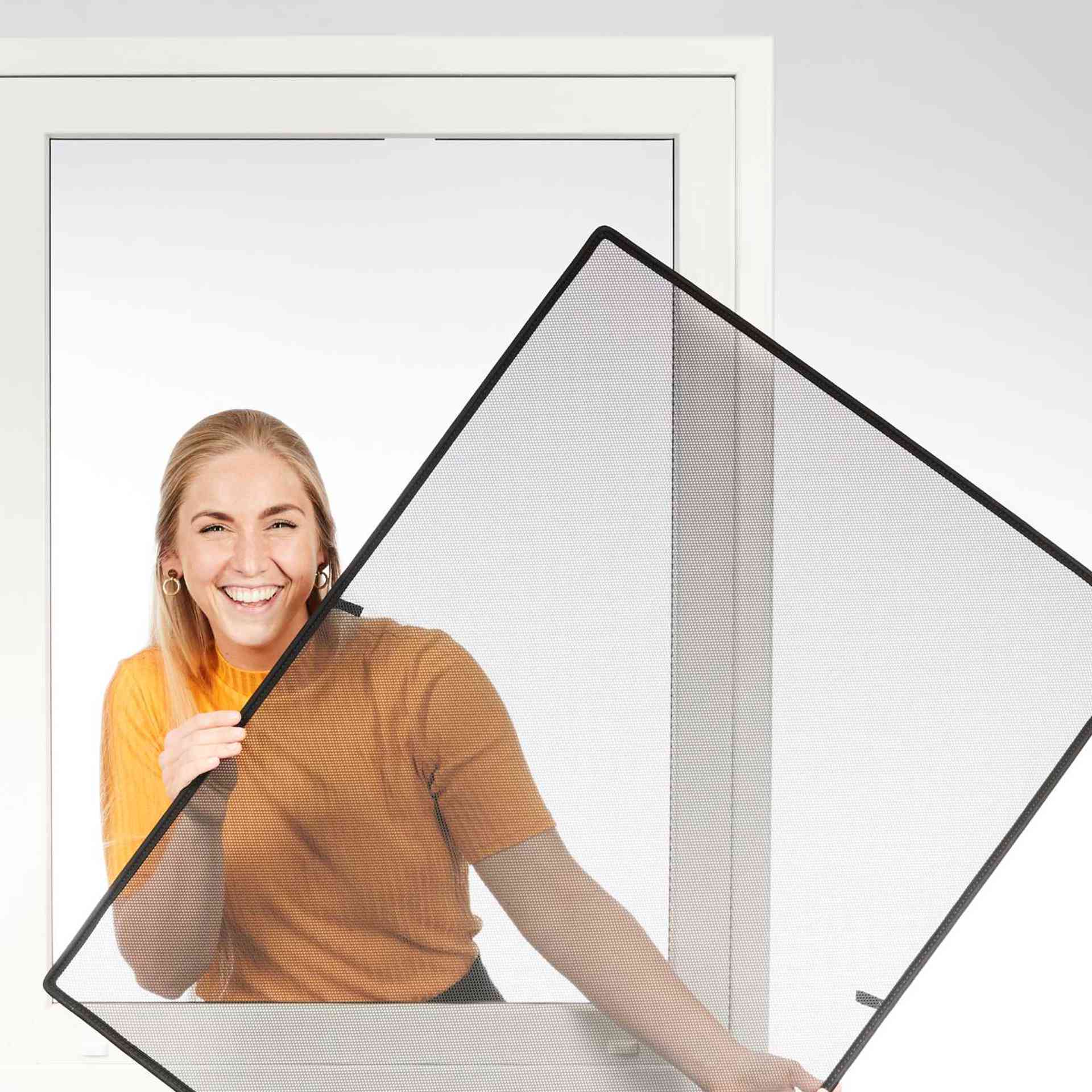 eine Frau hält lächelnd den WinClip Fensterschutz in den Händen