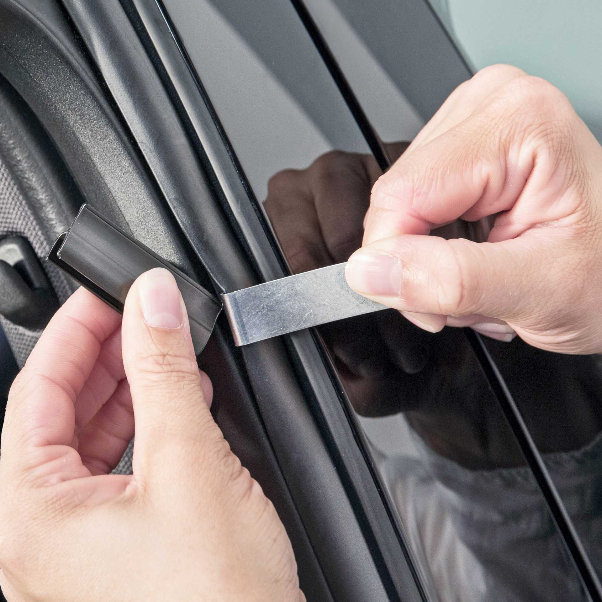 Jemand bringt einen Halter für die Sonnenblende an das Autofenster an